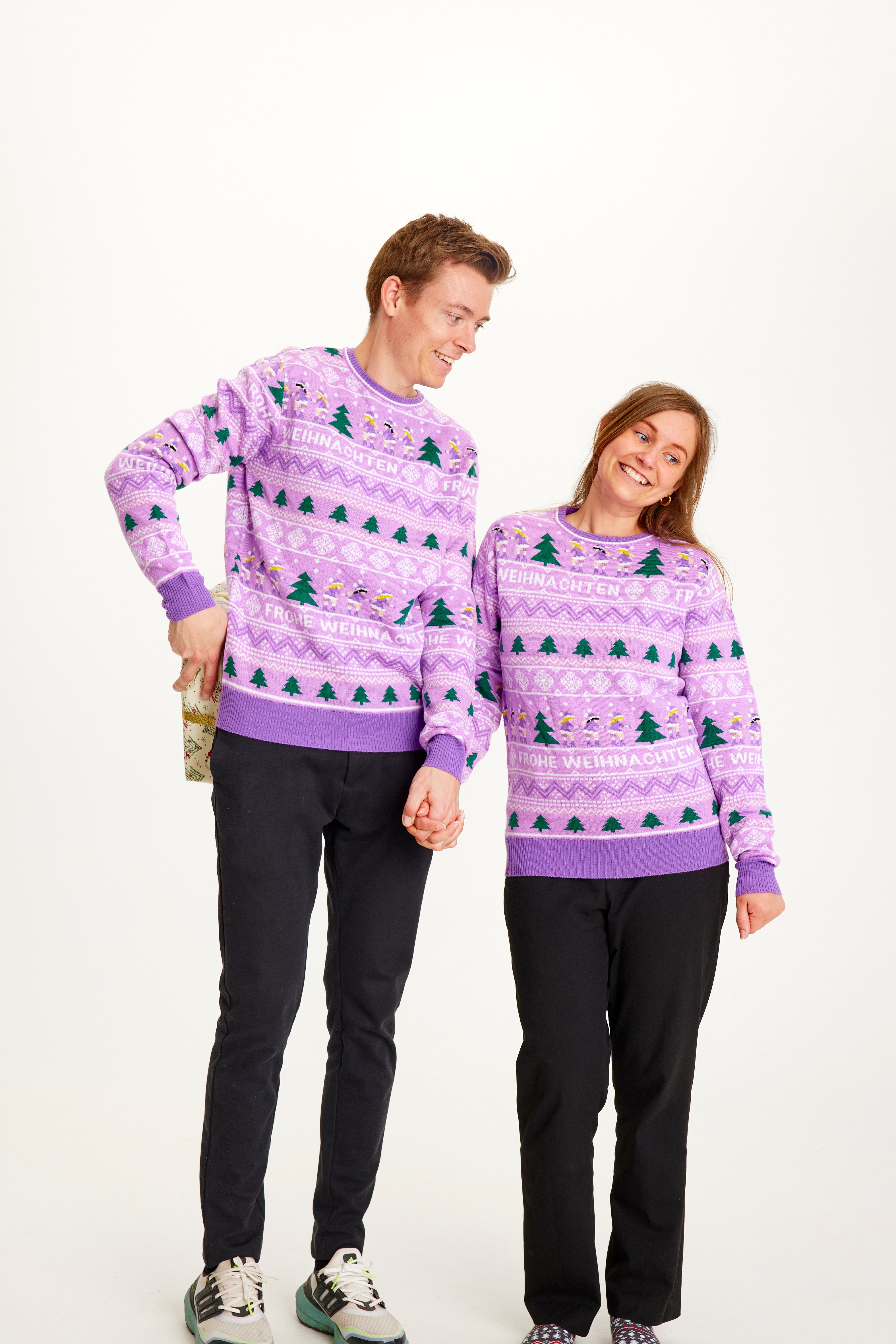 En mand og en dame holder i hånd og er iført samme julesweater.